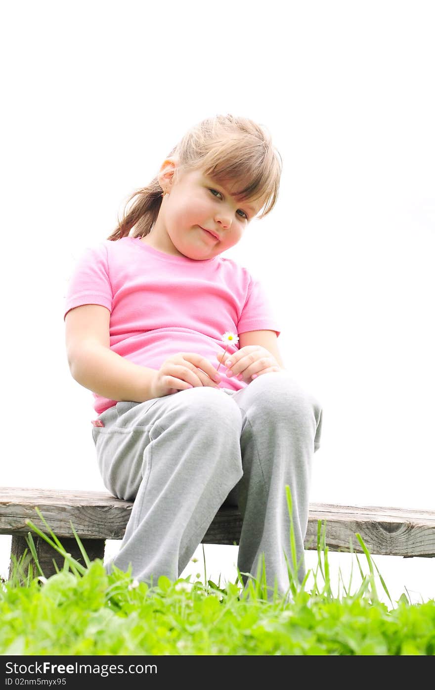 Girl sitting on a wooden bench in the grass. Girl sitting on a wooden bench in the grass