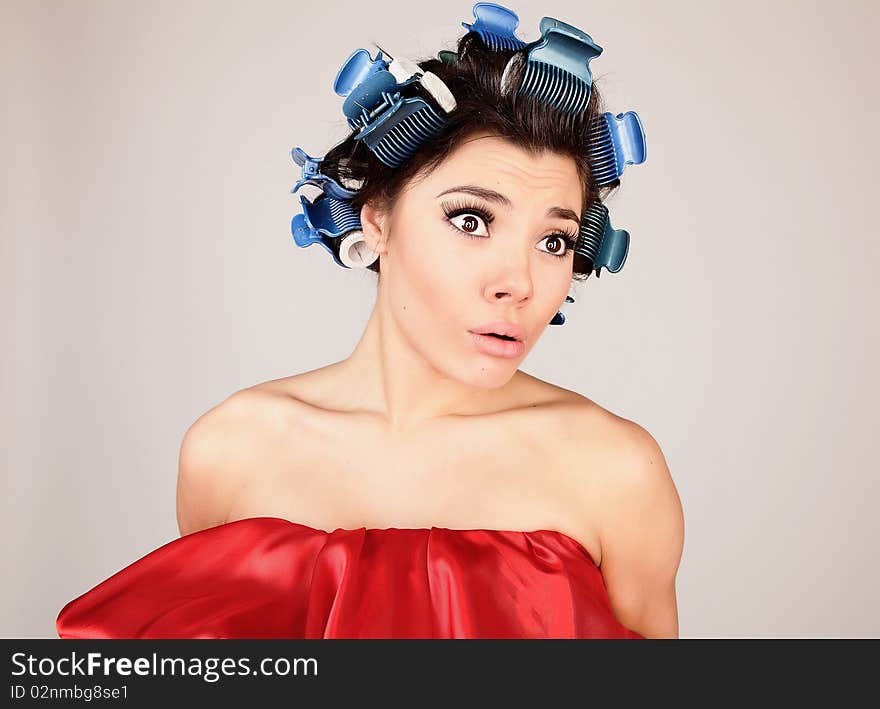 Emotional Girl with hair-curlers on her head. Photo.