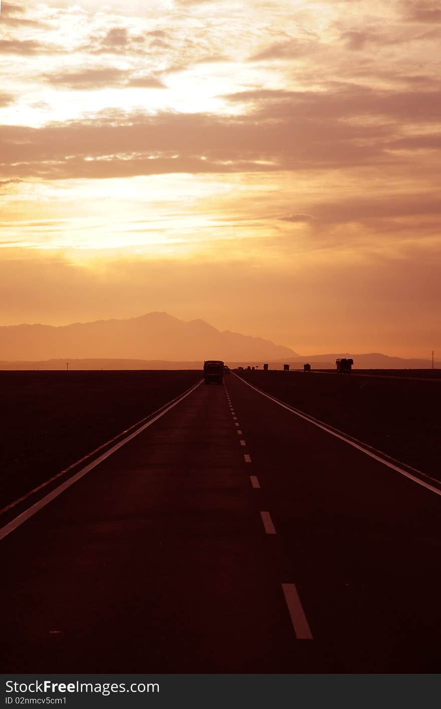 Sunset alsphalt highway and a lonely truck in the wilderness of Urumqi,Sinkiang,West China.