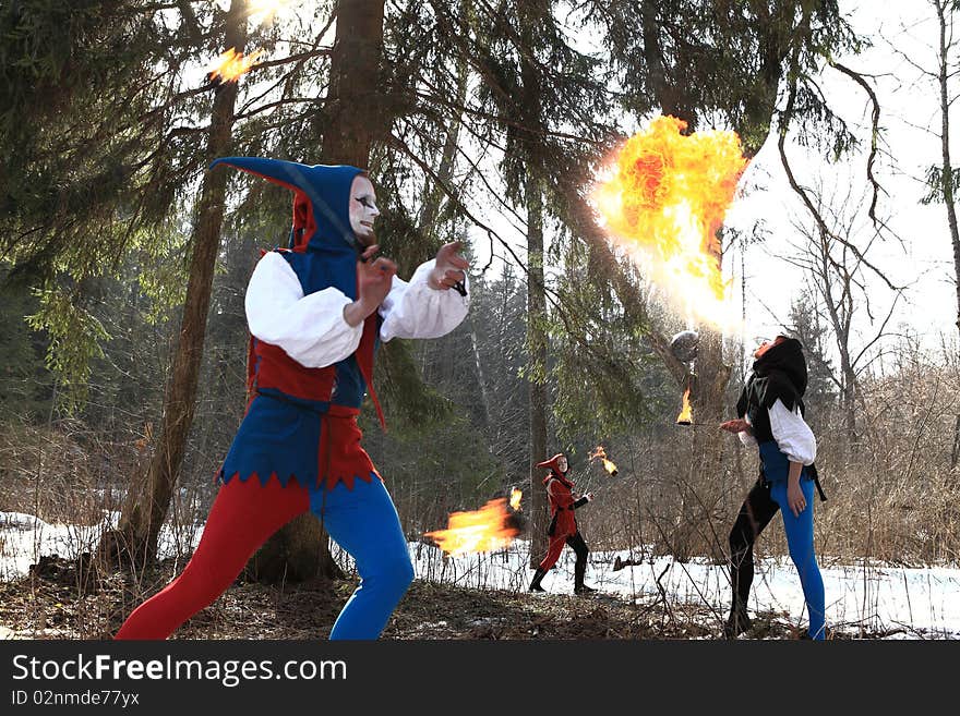 Group of retro fire-eater showing fire-show on forest.