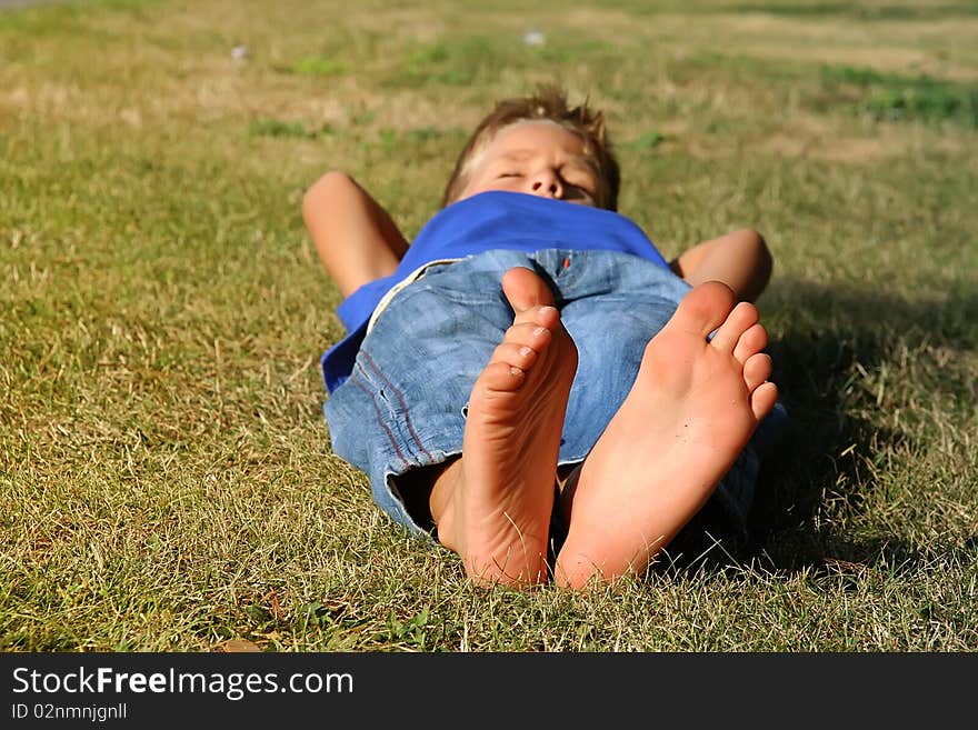 Happy young boy sleeping on the grass