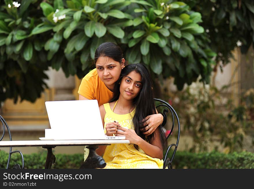 Mother and daughter sharing computer outdoors