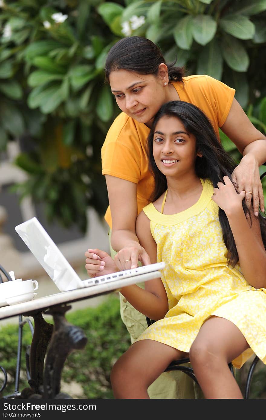 Mother and daughter working on laptop outdoors. Mother and daughter working on laptop outdoors