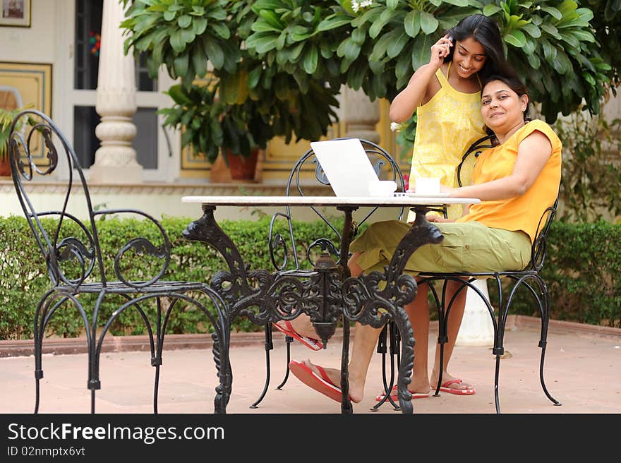 Mother working on computer with daughter in house garden. Mother working on computer with daughter in house garden