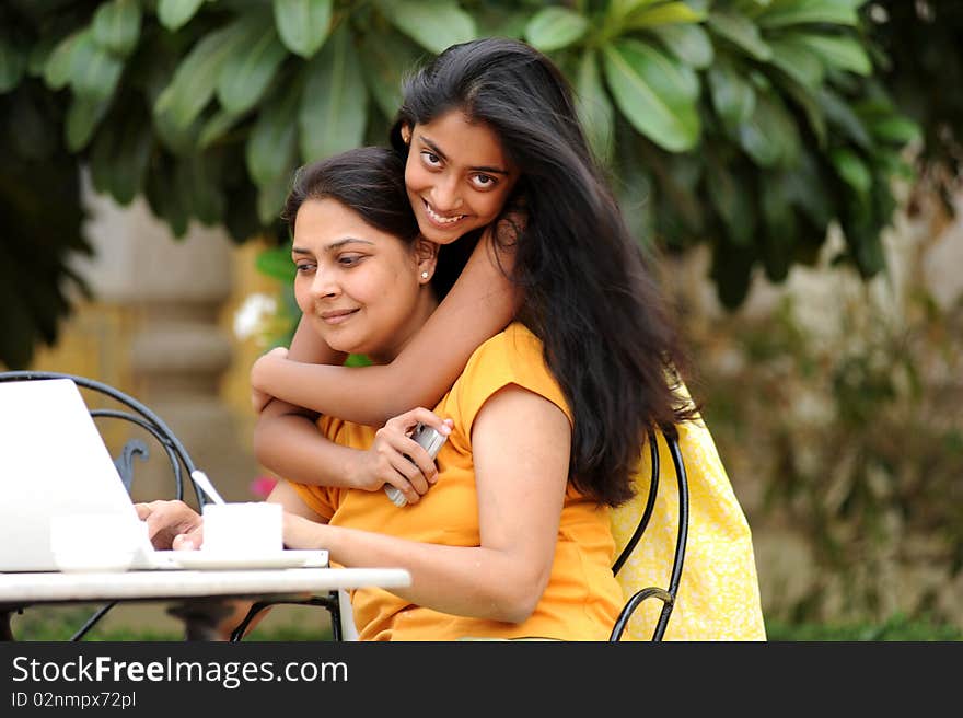 Mother working on computer with daughter in house garden. Mother working on computer with daughter in house garden