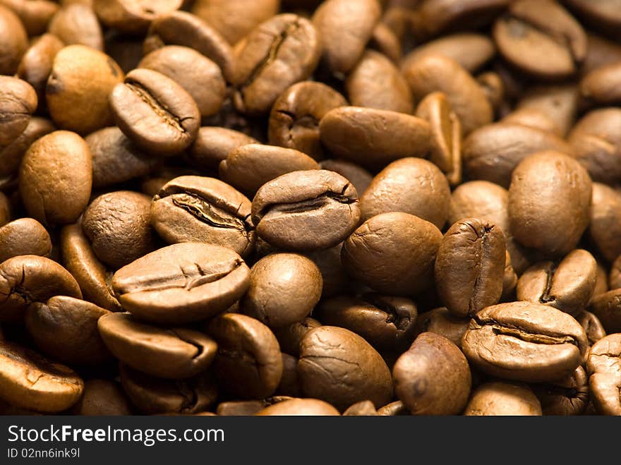 A closeup, macro view of a pile of whole, roasted coffee beans.