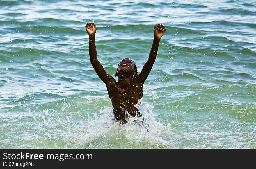 Young bahamian boy raising his arms in such joy after winning his swimming race. Young bahamian boy raising his arms in such joy after winning his swimming race.