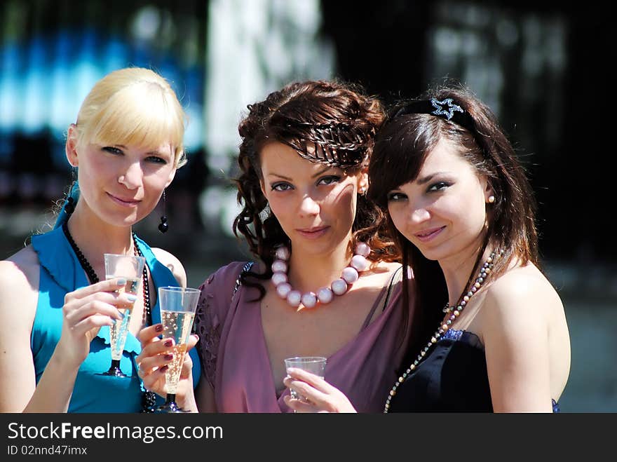 Three young women with glasses of a champagne in hands