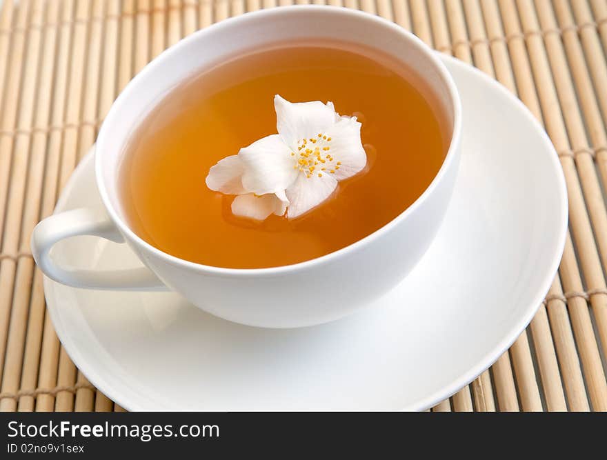 A white cup of tea on a tray with jasmine flower. A white cup of tea on a tray with jasmine flower