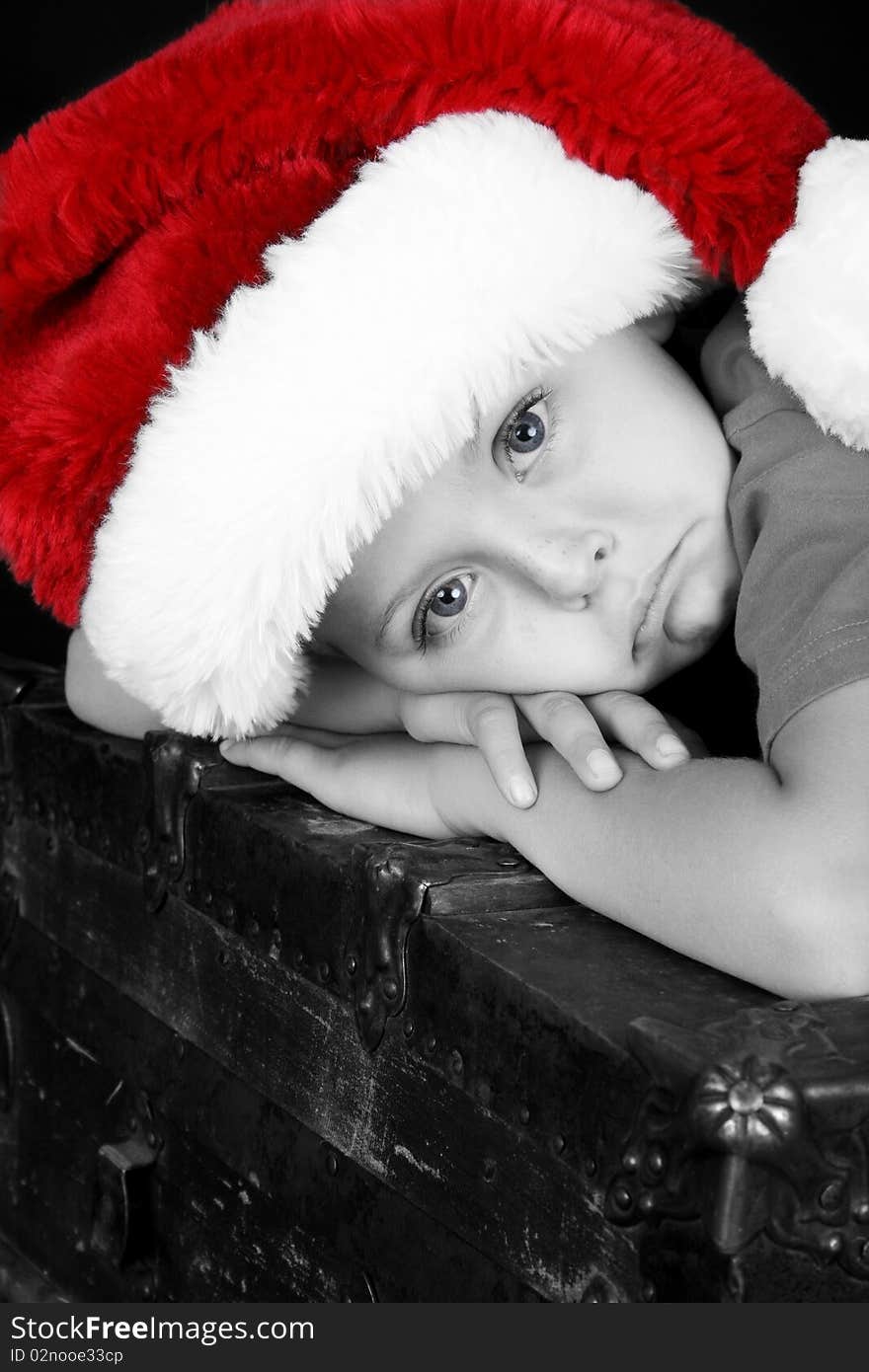 Beautiful boy lying on an antique chest with a sad expression. Beautiful boy lying on an antique chest with a sad expression