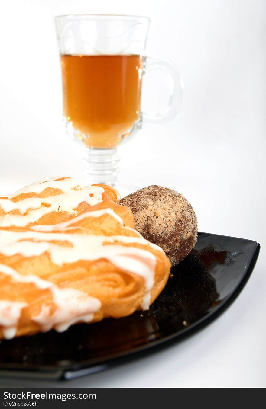 Three cakes on black plate with cup of tea  on white background. Three cakes on black plate with cup of tea  on white background