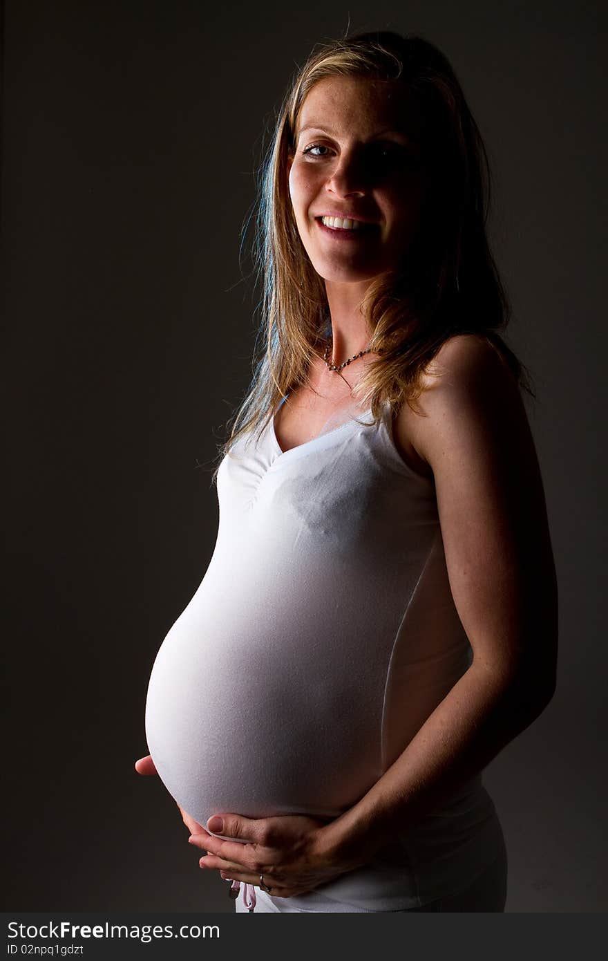 Young fresh pregnant woman with blow bubbles sitting on a couch over black background. Young fresh pregnant woman with blow bubbles sitting on a couch over black background.