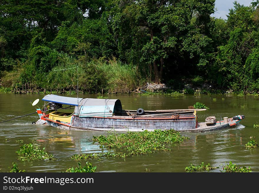 Heavily loaded river boat on Chao Praya River at Ayuttaya in Thailand. Clusters of water hyacinth floating along. Heavily loaded river boat on Chao Praya River at Ayuttaya in Thailand. Clusters of water hyacinth floating along.