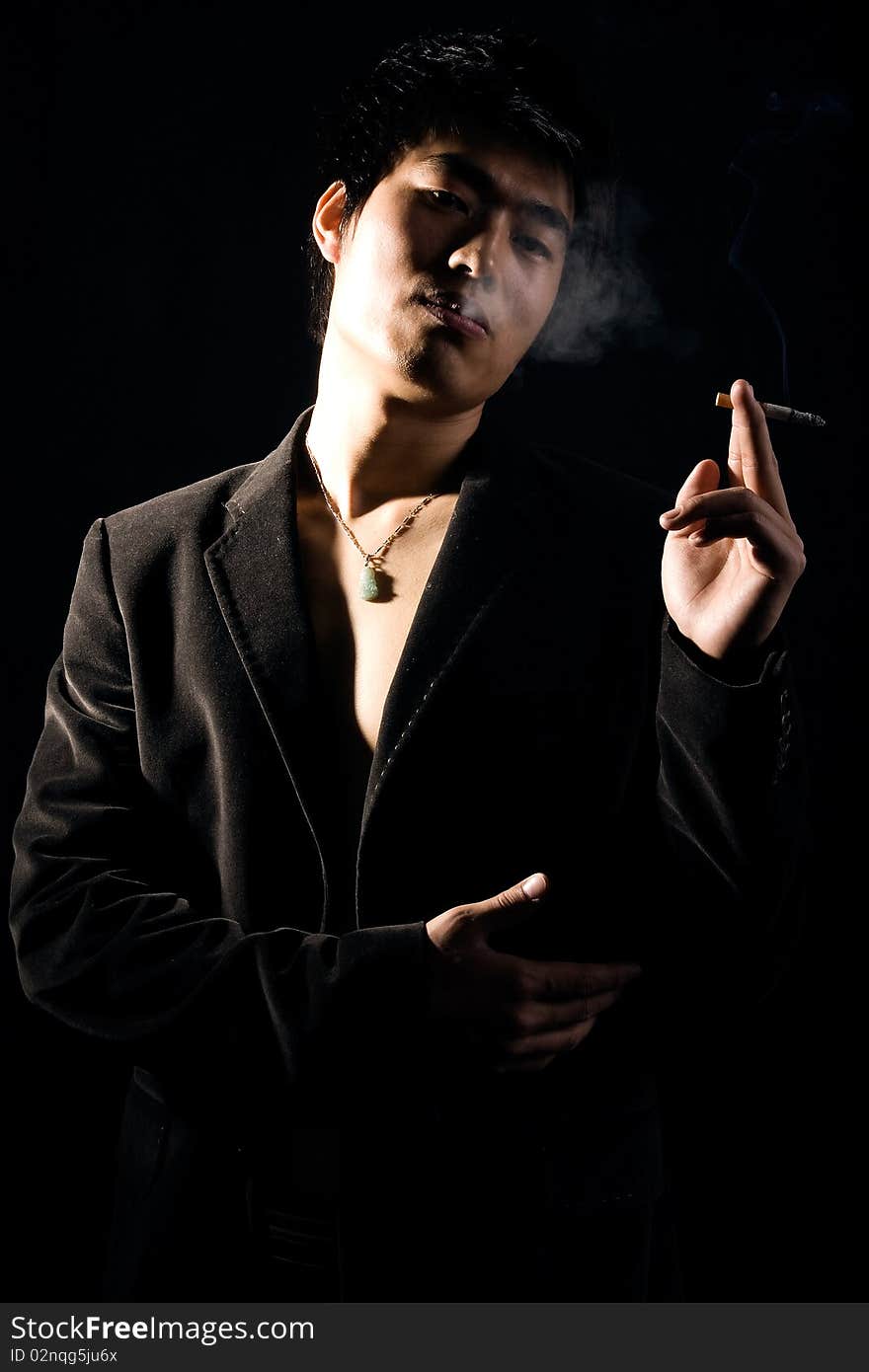 Handsome and fit man smoking on black background