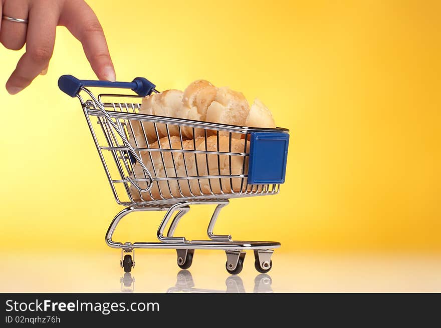 Metal shopping trolley filled with bread on yellow