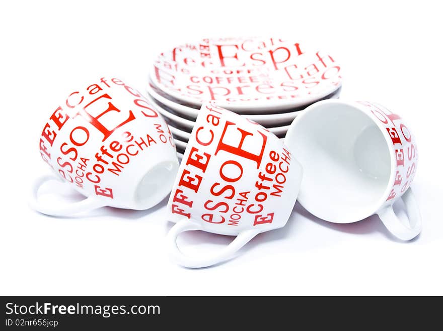 Three ceramic coffee cups lying around the stack saucers round shape, on a white background