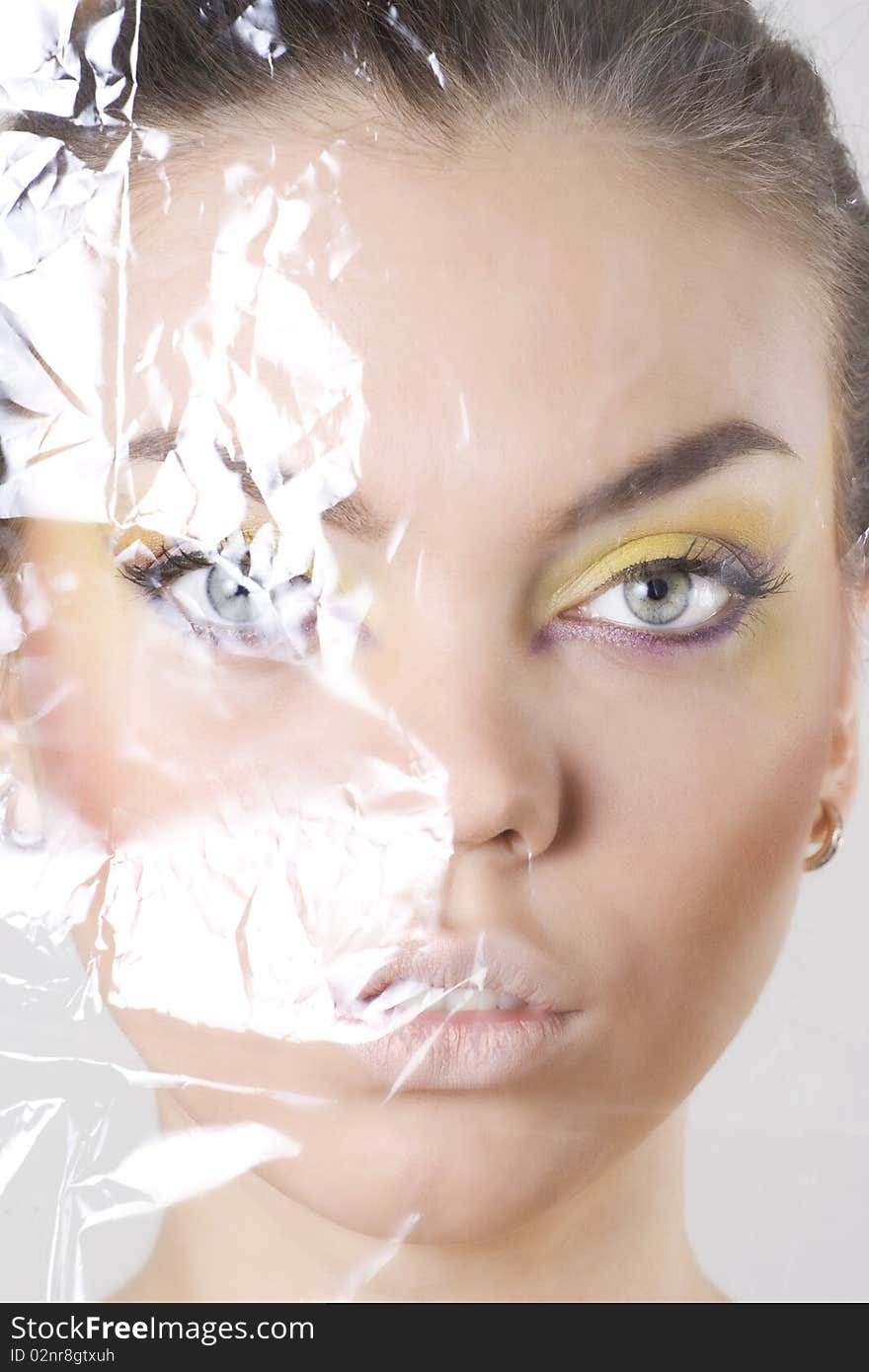 Closeup of a female face wrapped in cellophane.