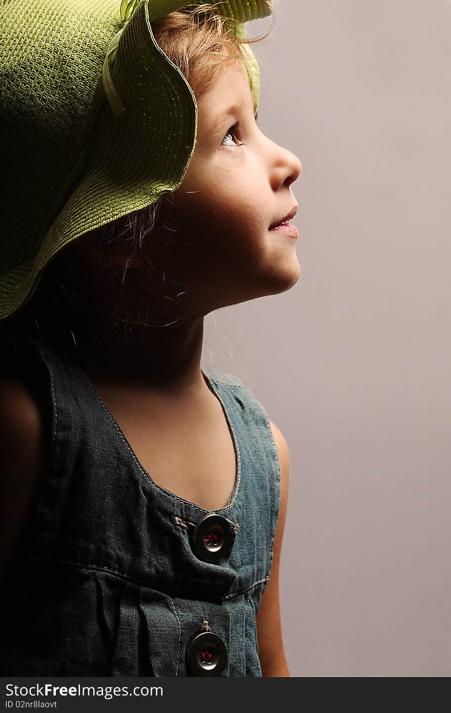 Portrait of little beautiful girl in a green hat