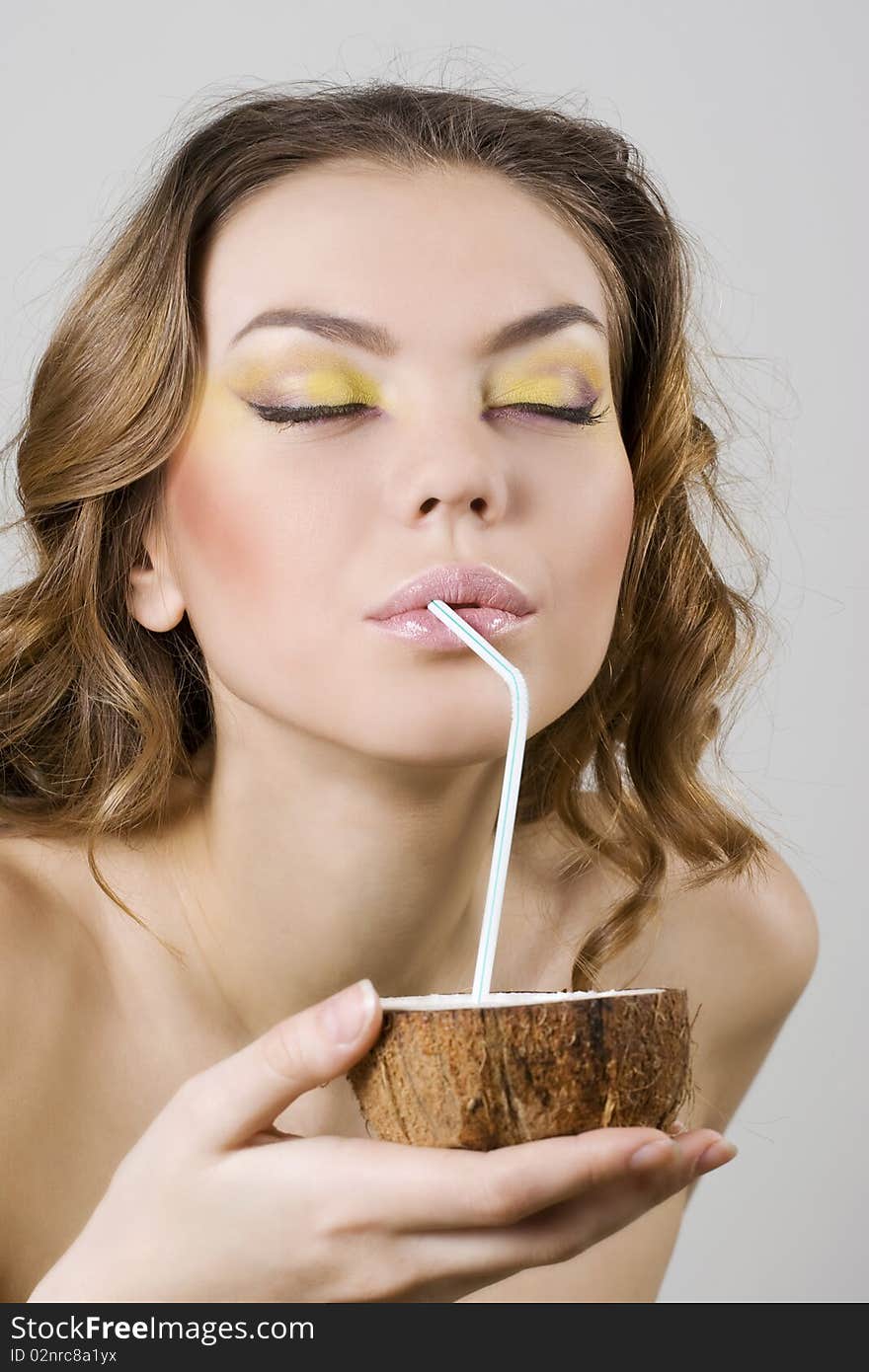 Young beautiful woman drinking coconut milk with a straw. Young beautiful woman drinking coconut milk with a straw