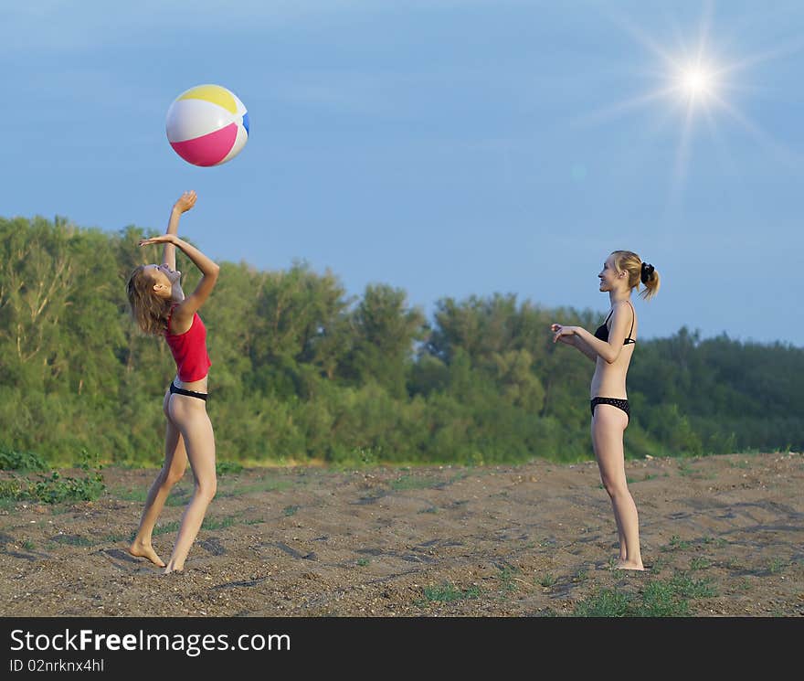 Young girls playing with a ball on the sandy beach