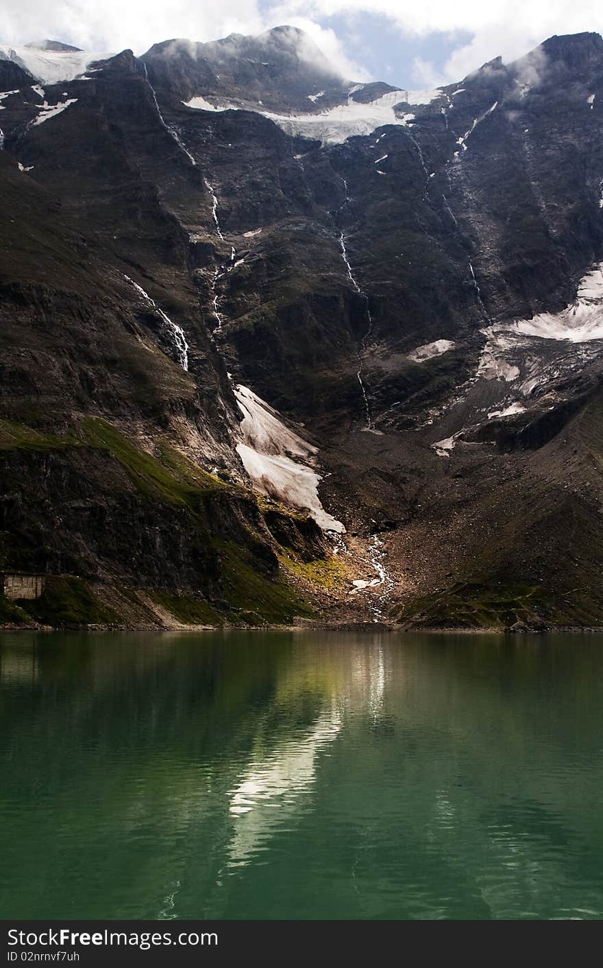 Melting glacier with reflection in the lake with dark background