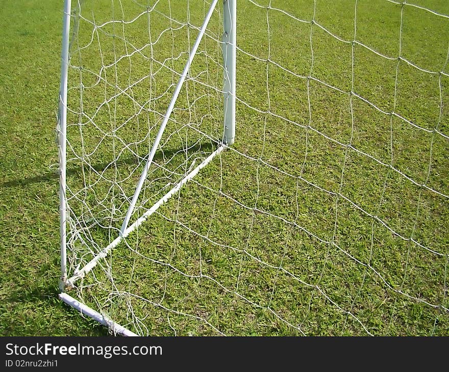 The goal net detail and green field. The goal net detail and green field