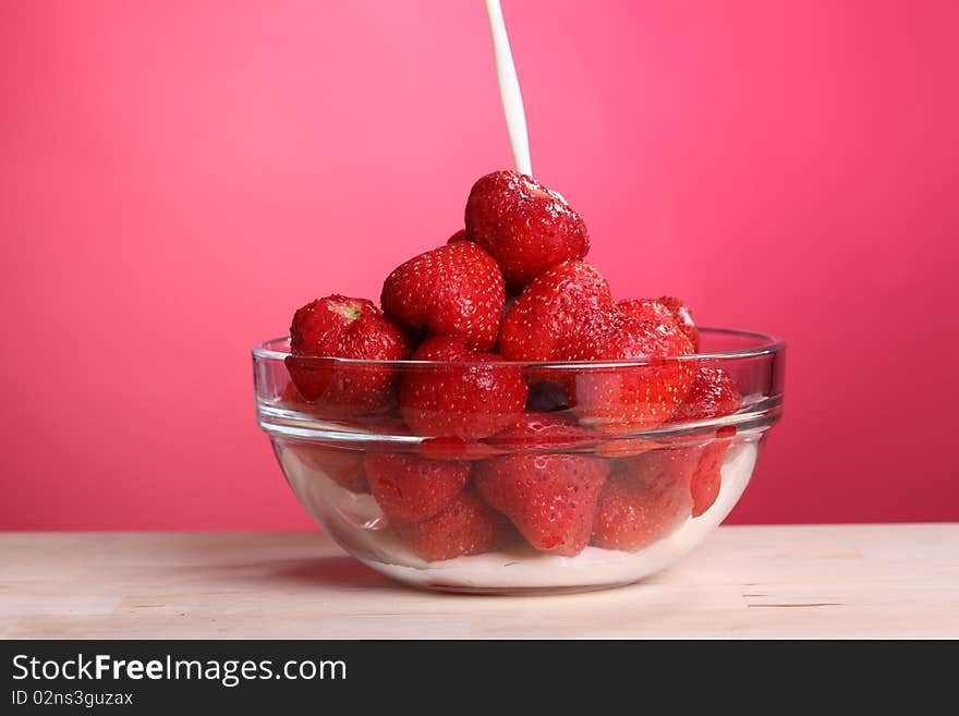 Close-up view of cream pouring into the bowl of fresh strawberry. Close-up view of cream pouring into the bowl of fresh strawberry