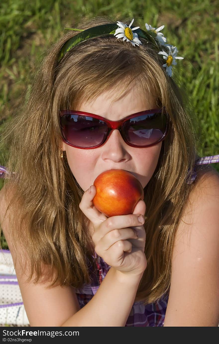 The portrait of the girl in summer day which eats peach