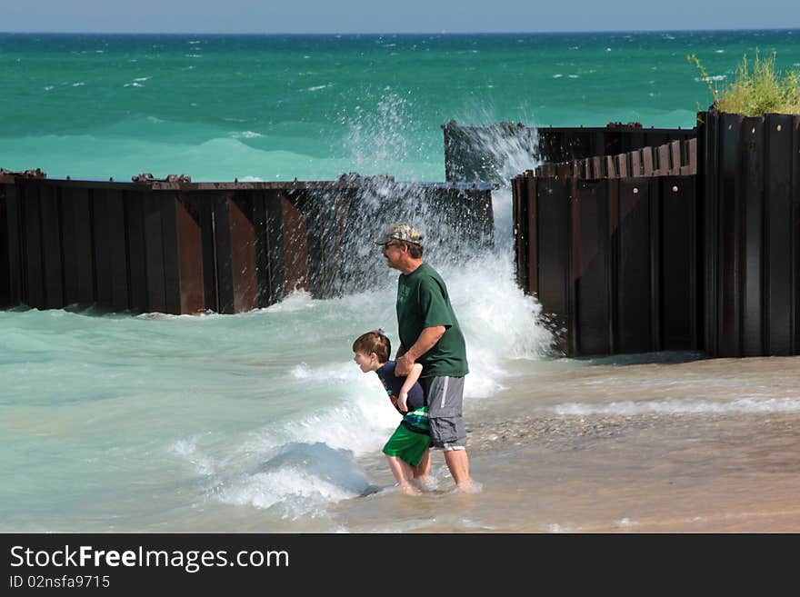 A young boy and his grandfather are standing near the shore and waves of lake Michigan. Taken at the breakwall at Point Betsie beach. A young boy and his grandfather are standing near the shore and waves of lake Michigan. Taken at the breakwall at Point Betsie beach.