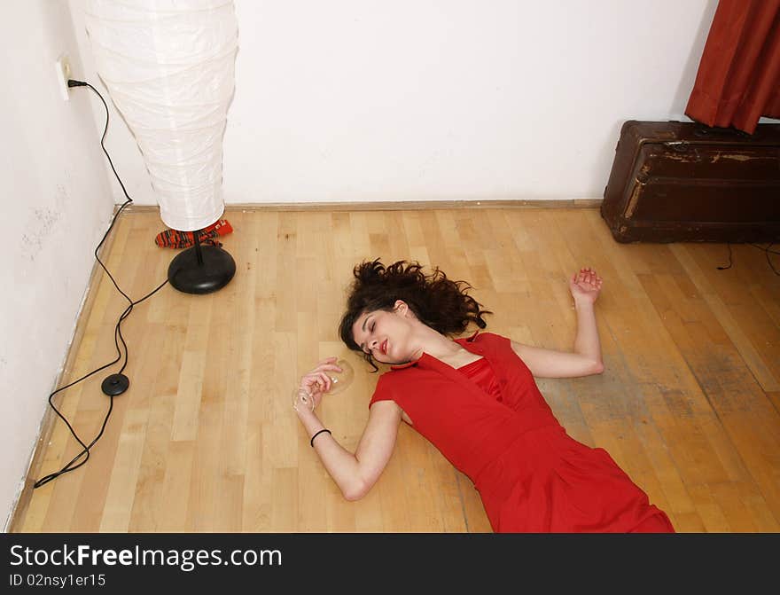 Woman in red dress lying on the ground with win glass