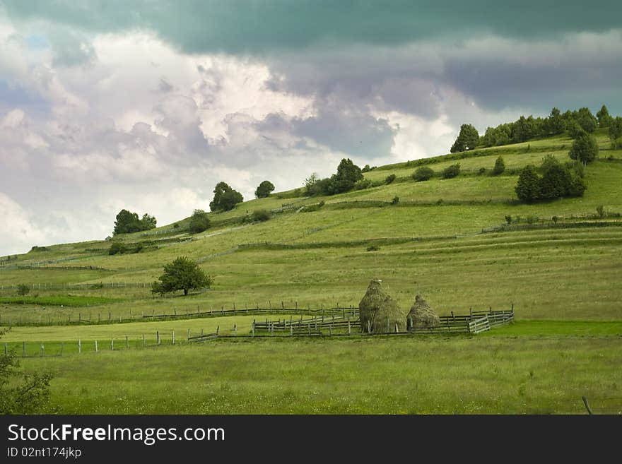 Mountain pasture landscape with haystacks, spectacular cloudscape in Transylvania, Romania