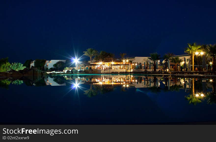 Tropical resort reflected in a pool at night