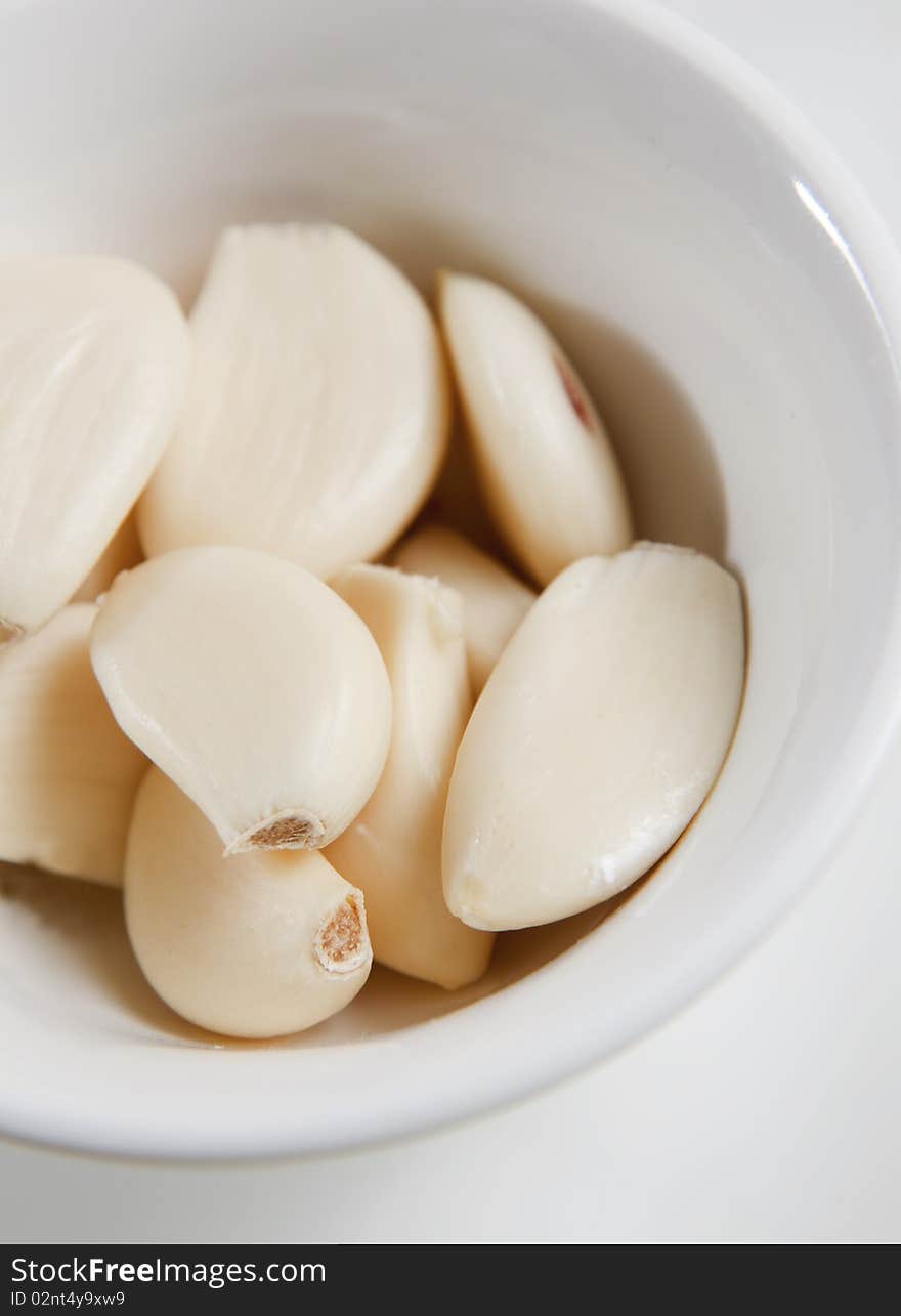 Peeled garlic cloves in white bowl, ready as ingredient. Peeled garlic cloves in white bowl, ready as ingredient.