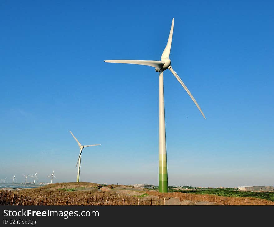 Wind turbines near the beach under blue sky. Wind turbines near the beach under blue sky