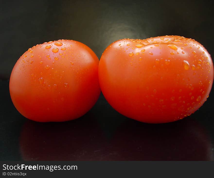 The vegetables - two red tomatoes on black background. The vegetables - two red tomatoes on black background