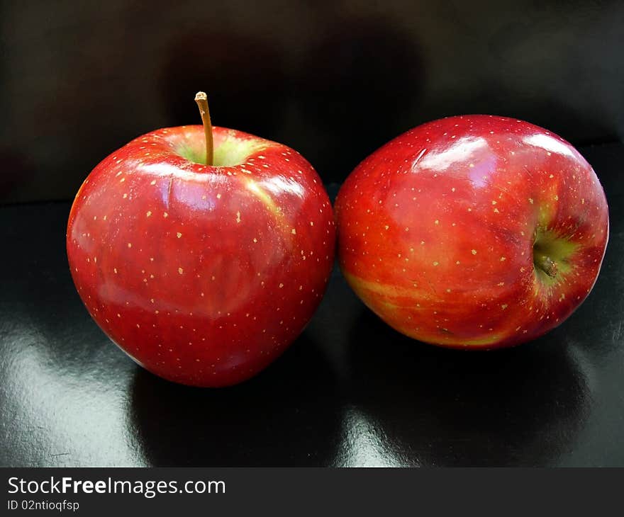 Two red apples on a black background