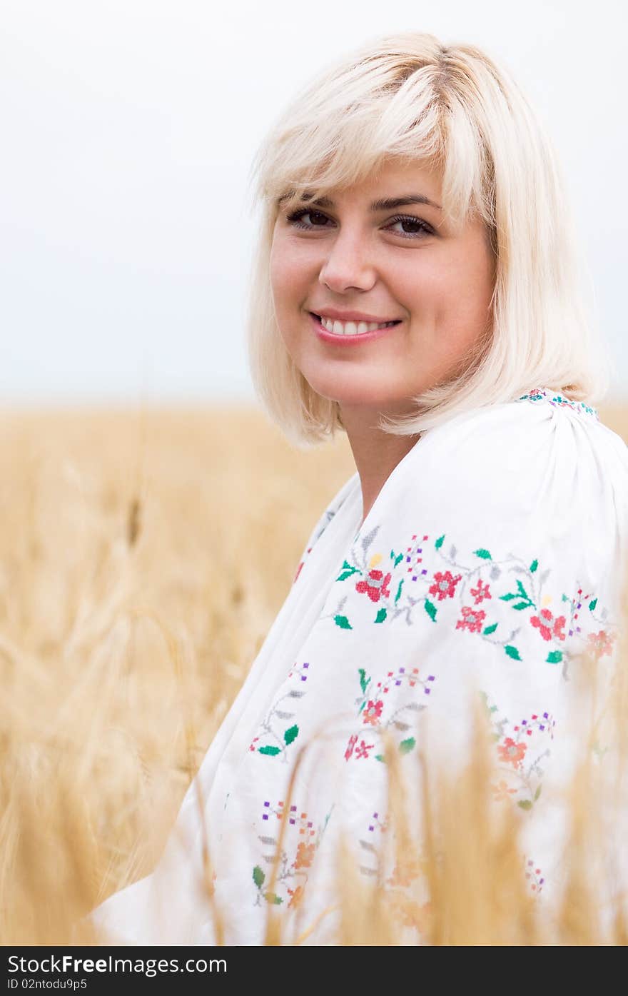 Beautiful woman in a national Ukrainian suit in wheat meadow on sunny day