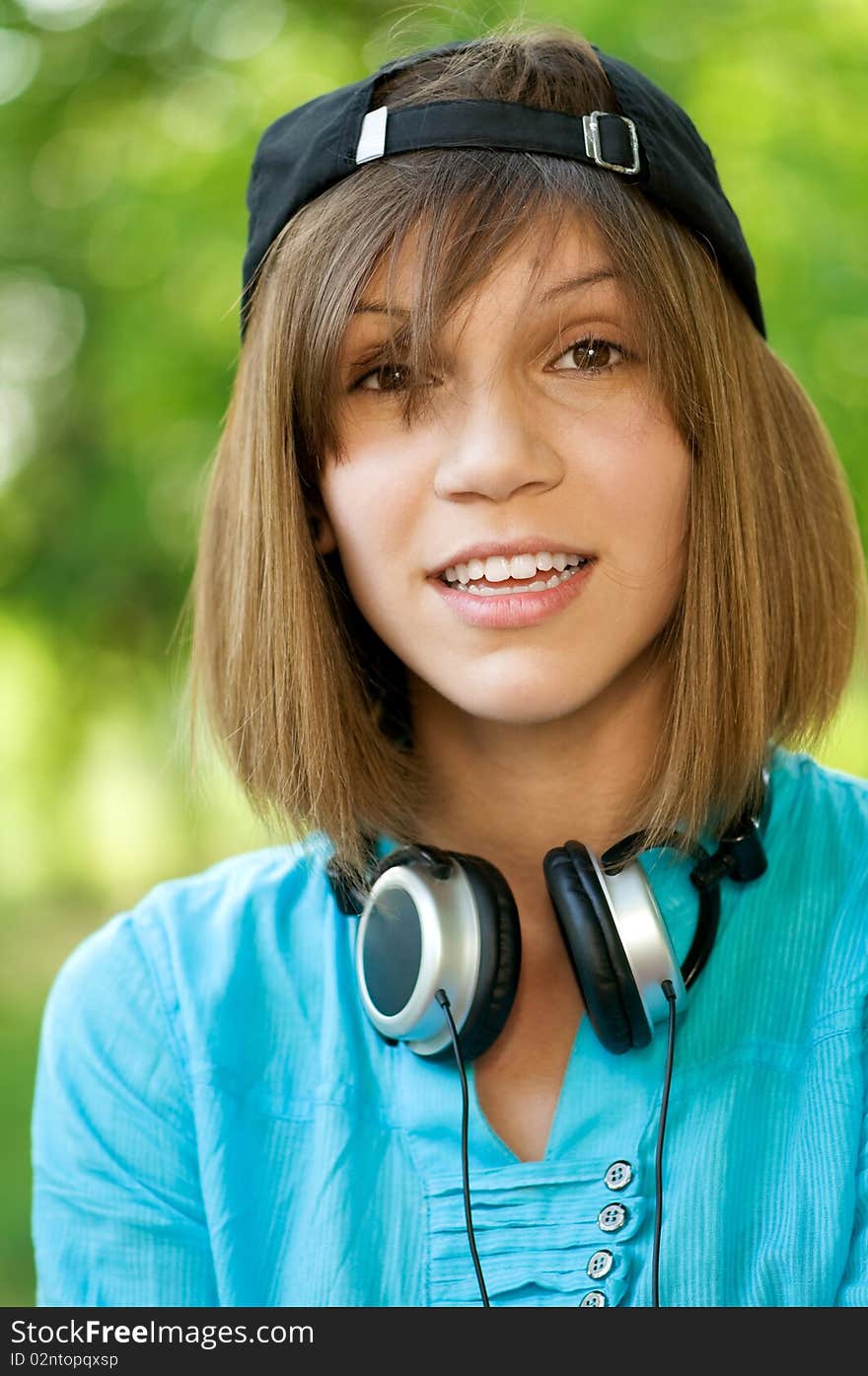 Beautiful teenage girl with headphones in the green park