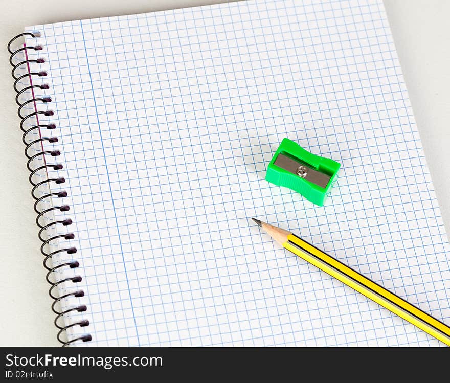 Sharp pencil and sharpener on a spiral notebook in blank