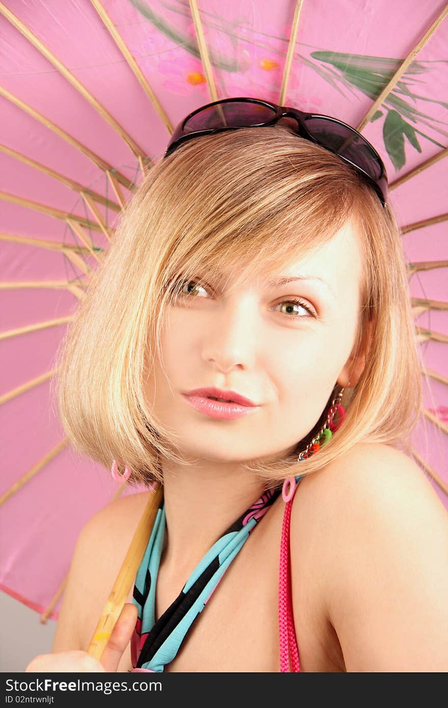 Portrait of girl with pink umbrella in studio over grey