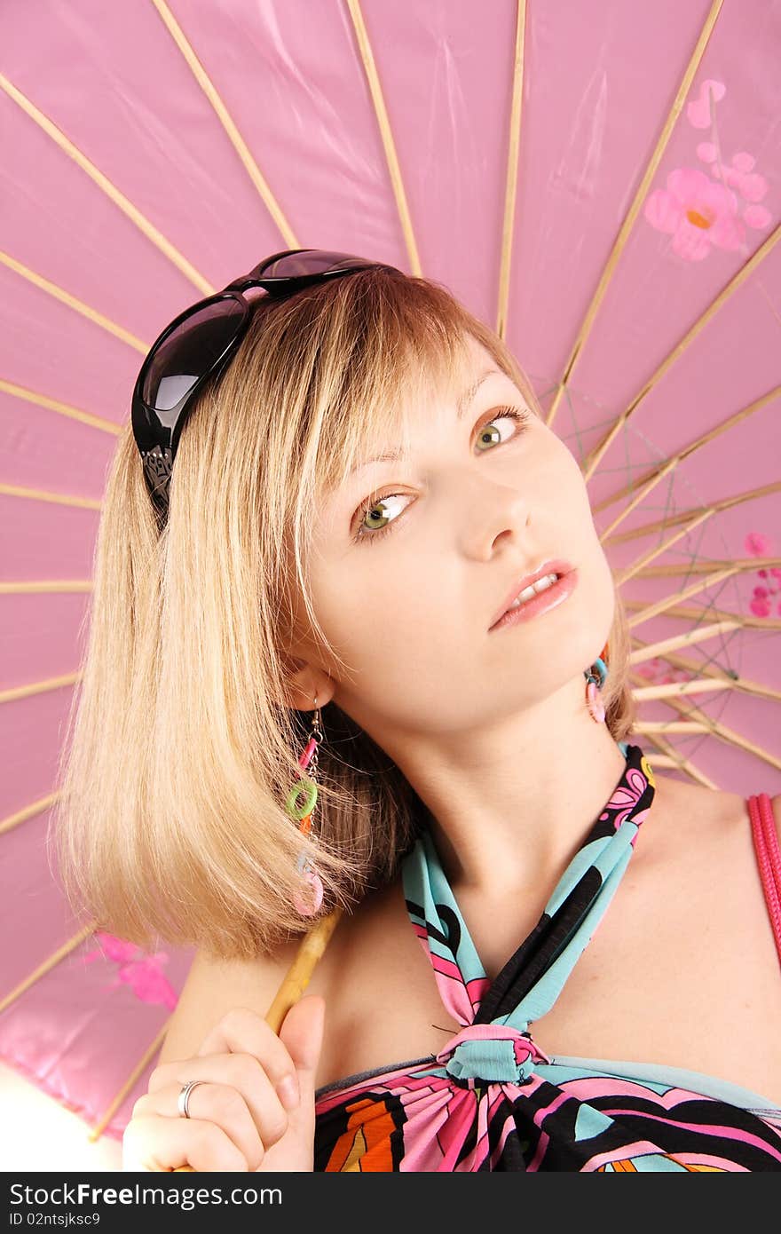 Portrait of girl with pink umbrella in studio over grey