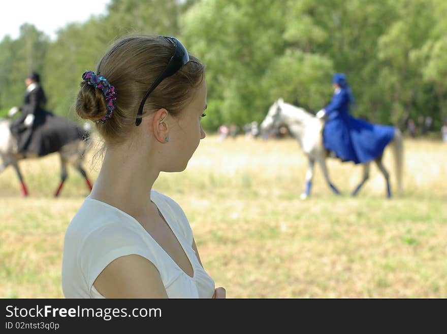 Girl watching a horsewoman ride in blur. Girl watching a horsewoman ride in blur