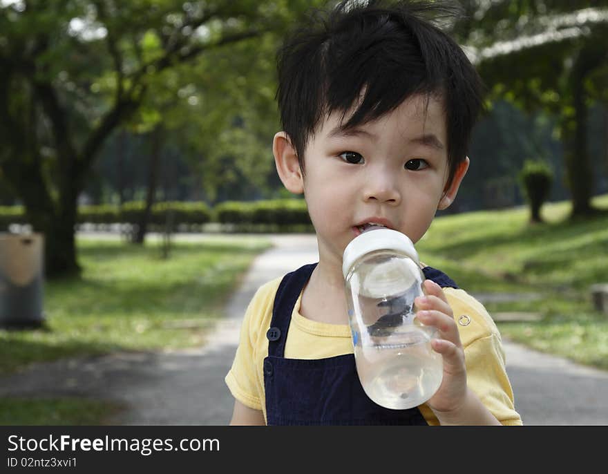 A small boy drinking from a bottle. A small boy drinking from a bottle