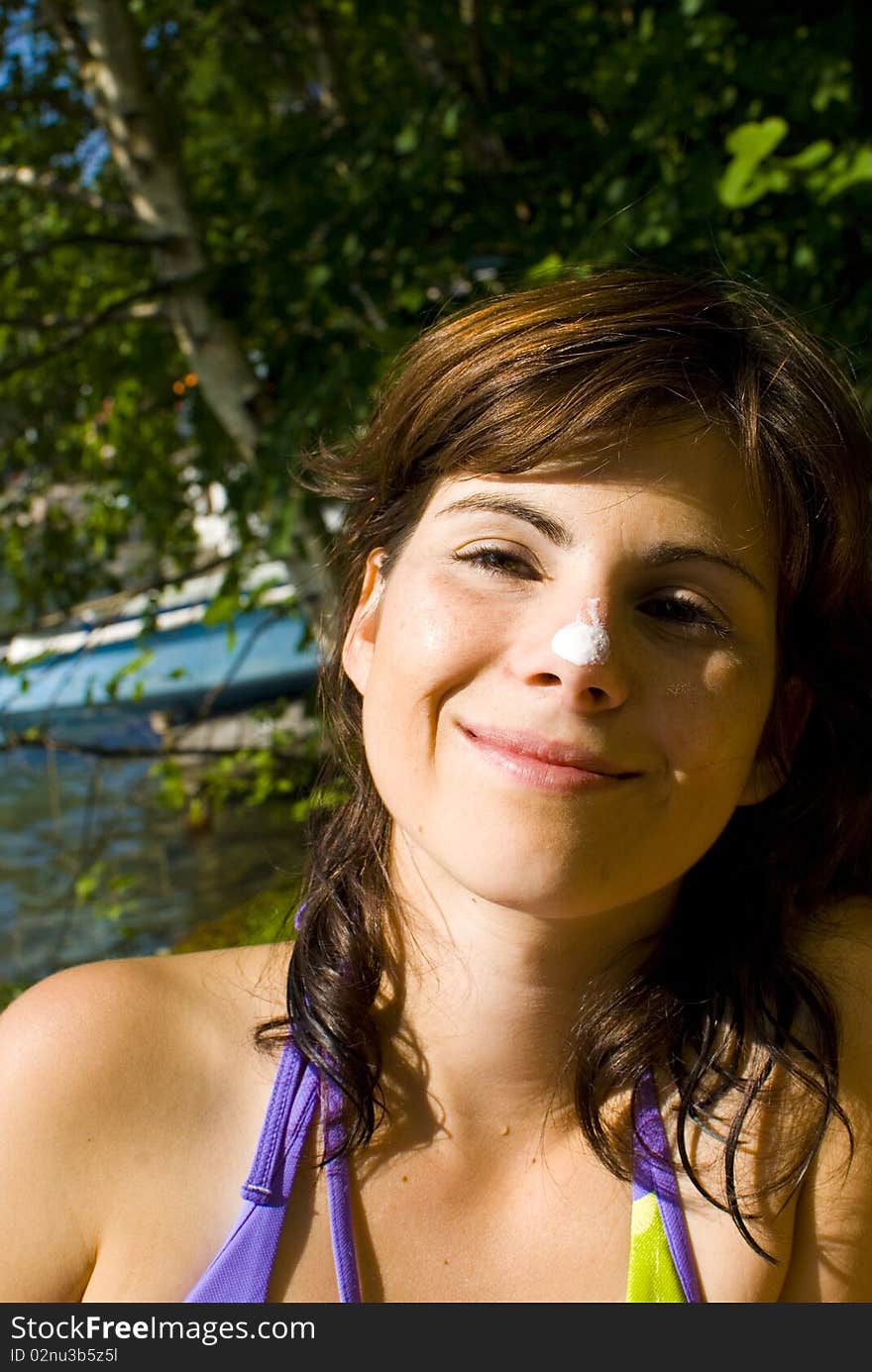 Young woman at the beach with sunscreen on her nose.