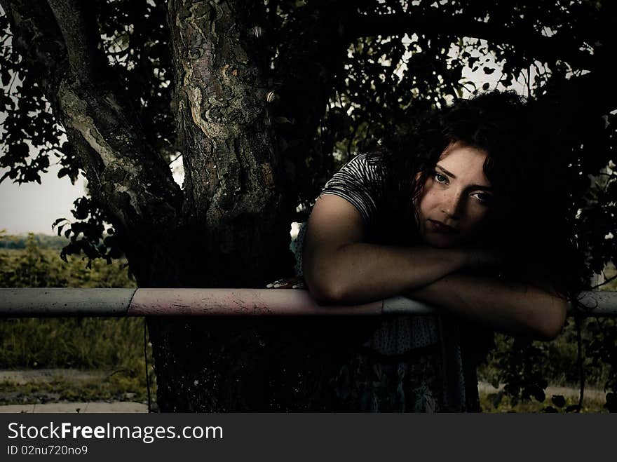 Young redhead woman at fence under apple tree. Young redhead woman at fence under apple tree