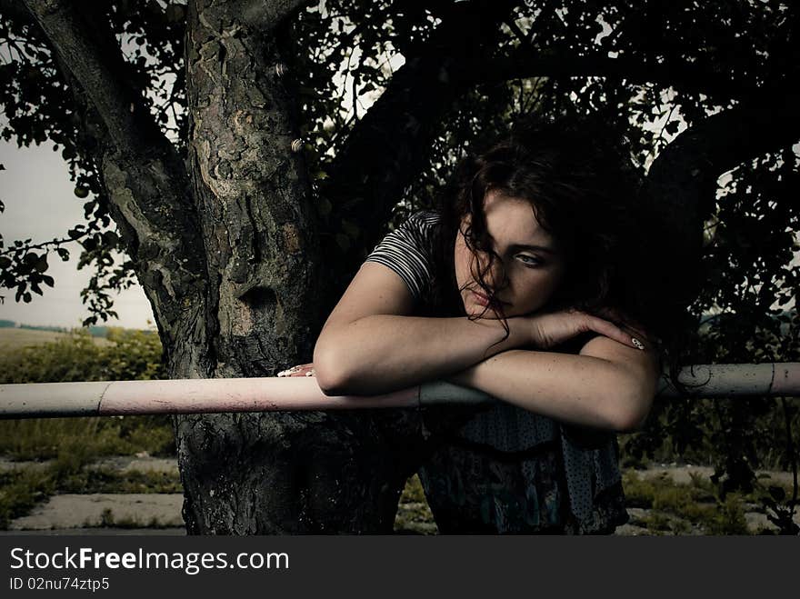 Young redhead woman at fence under apple tree. Young redhead woman at fence under apple tree