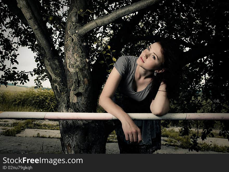 Young redhead woman at fence under apple tree. Young redhead woman at fence under apple tree