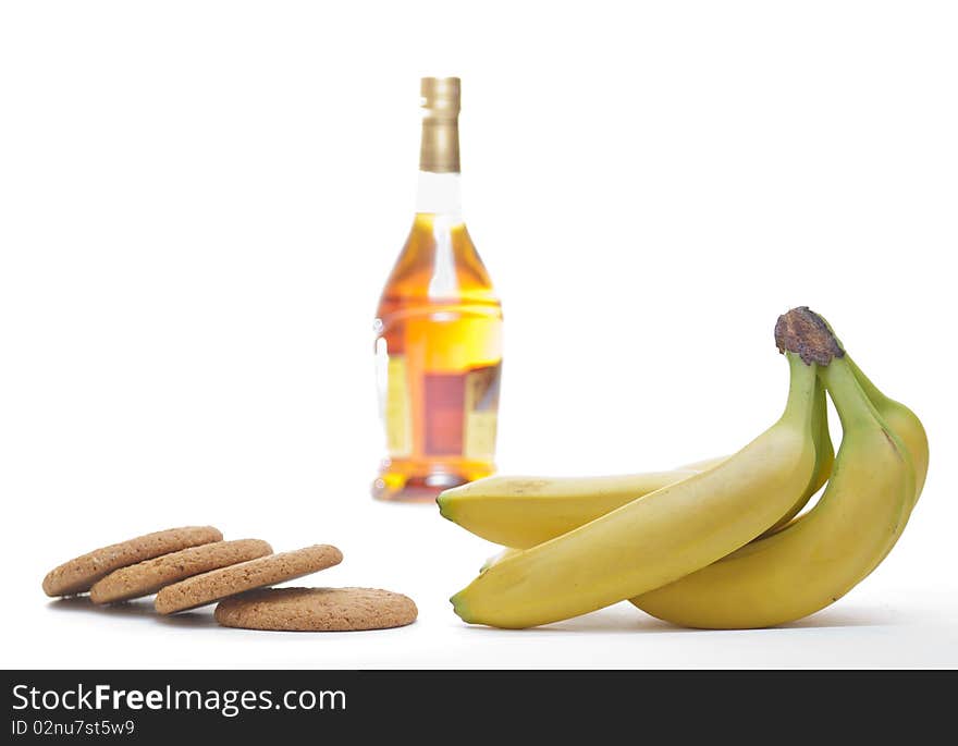 Bottle of  brandy, yellow banana and cookie isolated. Bottle of  brandy, yellow banana and cookie isolated