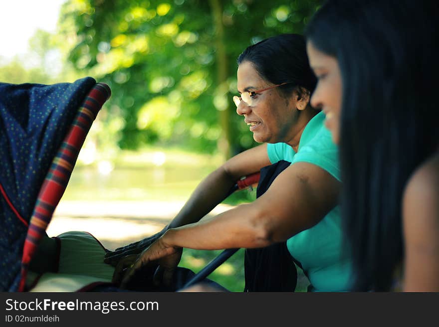 A mother and a grandmother looking at a baby in a carriage. A mother and a grandmother looking at a baby in a carriage