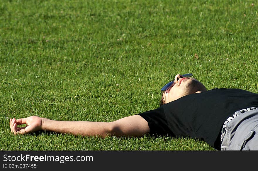 Young man laying on green grass relaxing and finding inner peace. Young man laying on green grass relaxing and finding inner peace